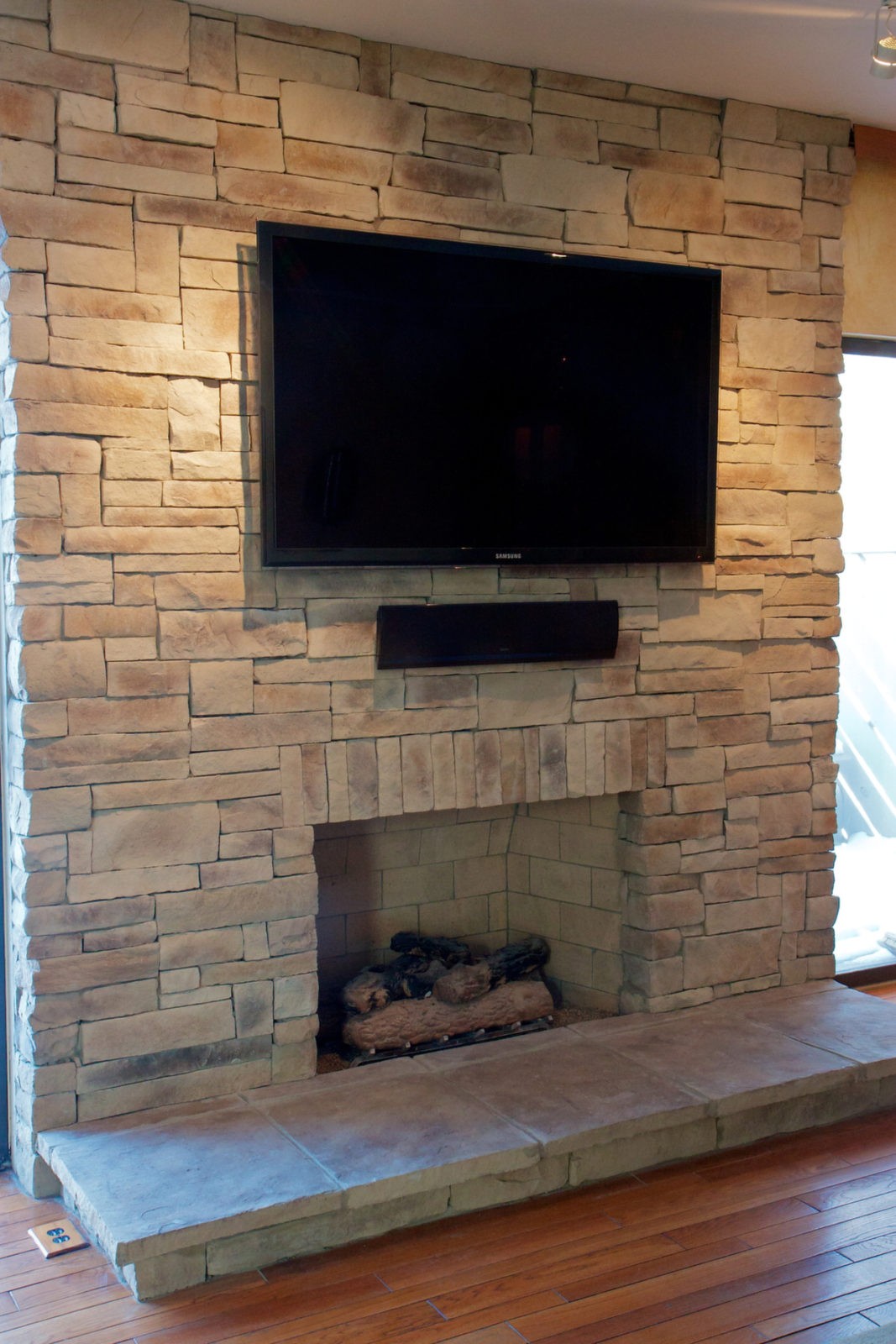 Tan mountain ledgestone dry stack veneer fireplace with a TV