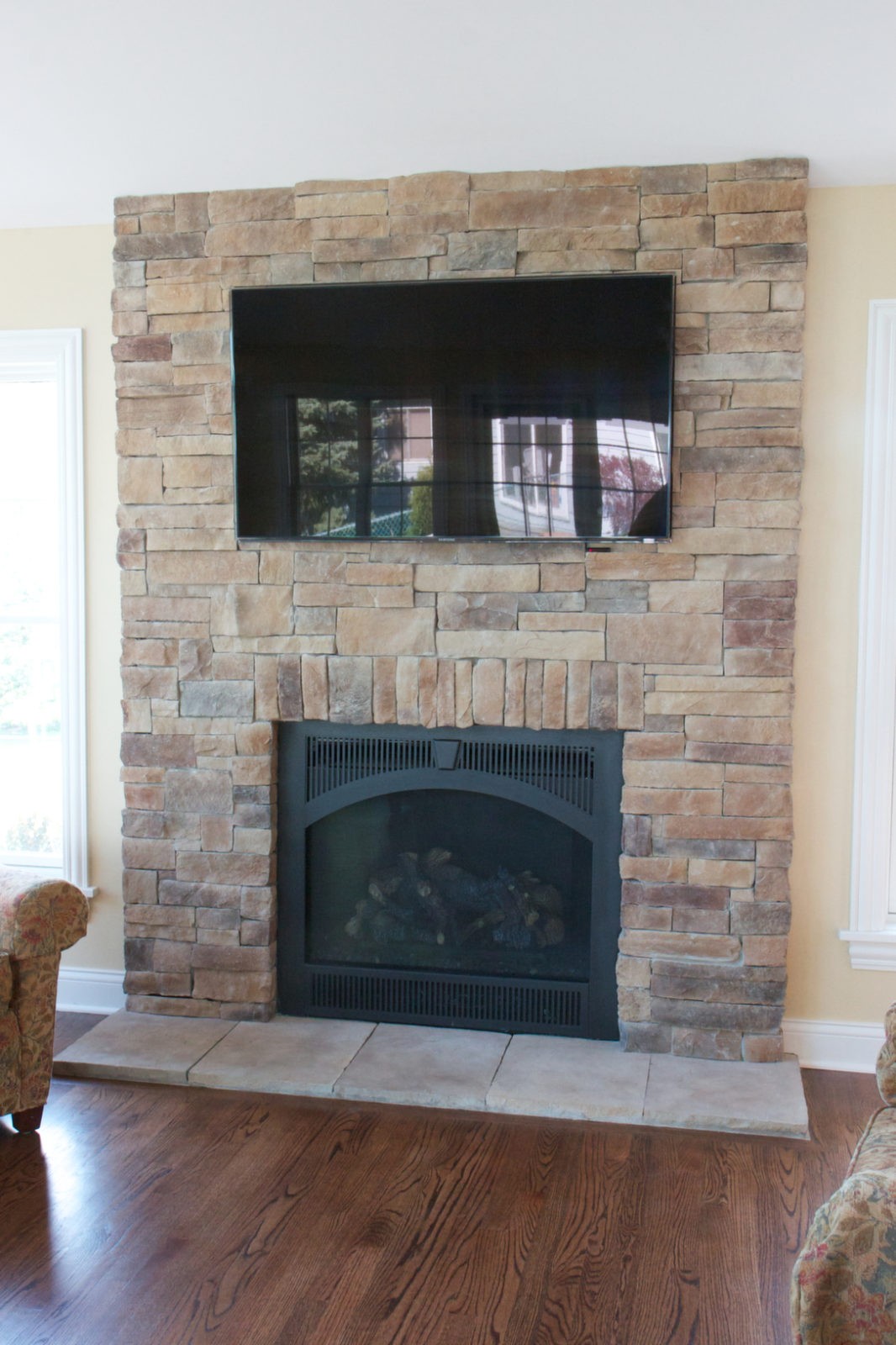 Mountain stack stone veneer fireplace with a fireplace screen and a TV