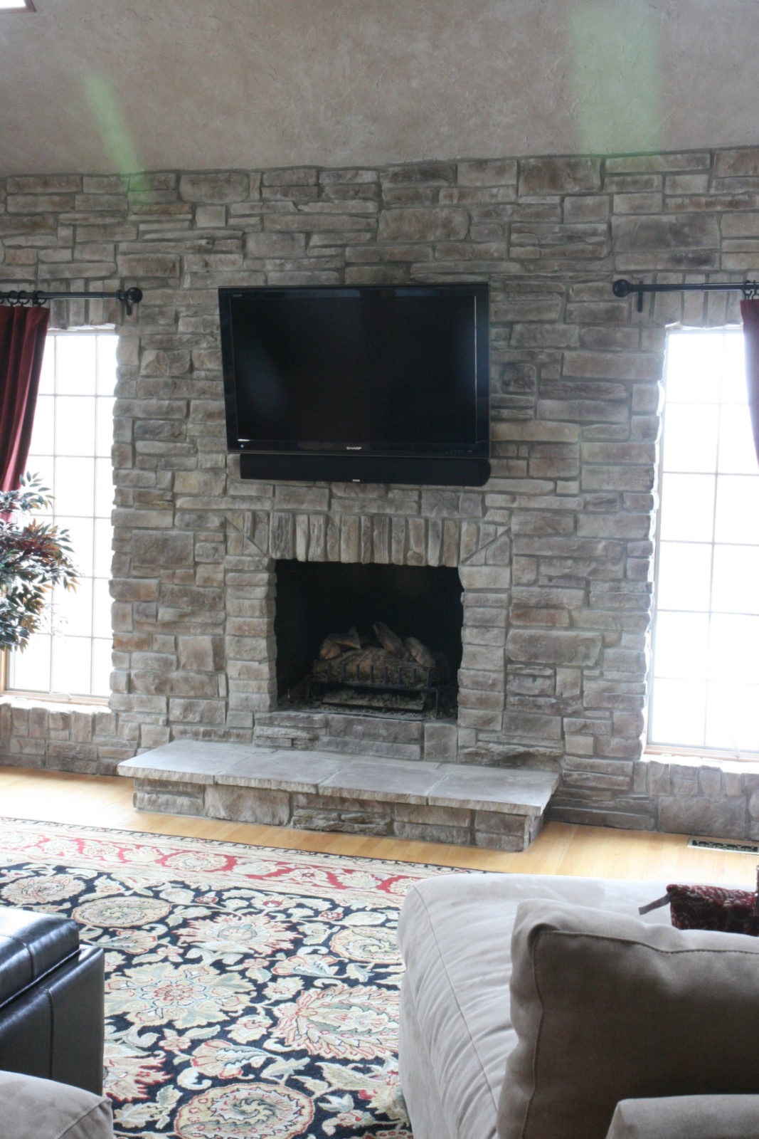 Gray mountain stack stone veneer fireplace in a brightly lit living room