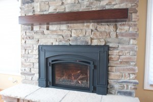 Our stone work: a stone veneer fireplace with a wooden mantle