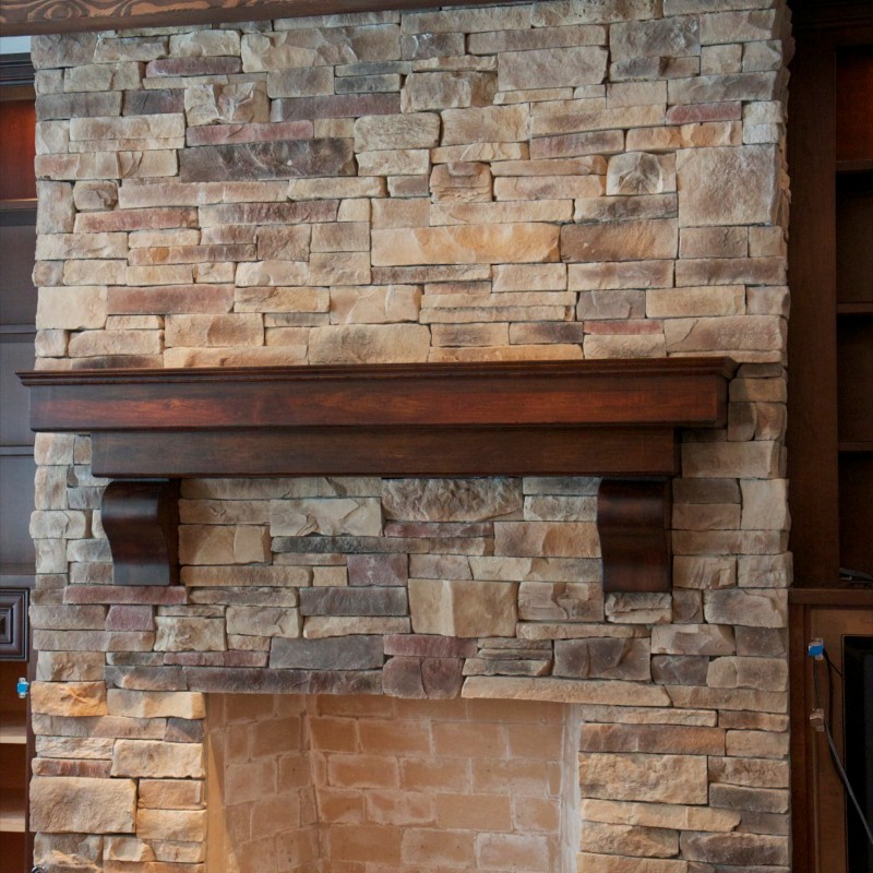 Mountain ledge stone veneer fireplace surrounded by wooden built-in cabinets