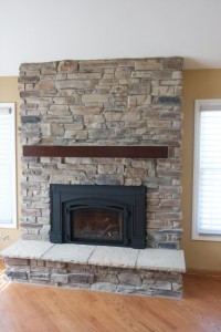 Mountain Ledge Stone Veneer fireplace with a wooden mantle