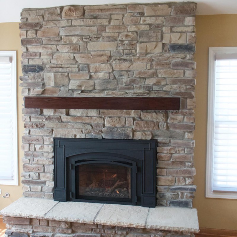 Mountain Ledge Stone Veneer fireplace with a wooden mantle